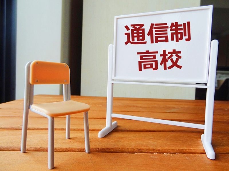 「通信制高校」と書いたホワイトボードに教室の椅子