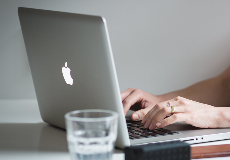 MacBookのアップと操作する手